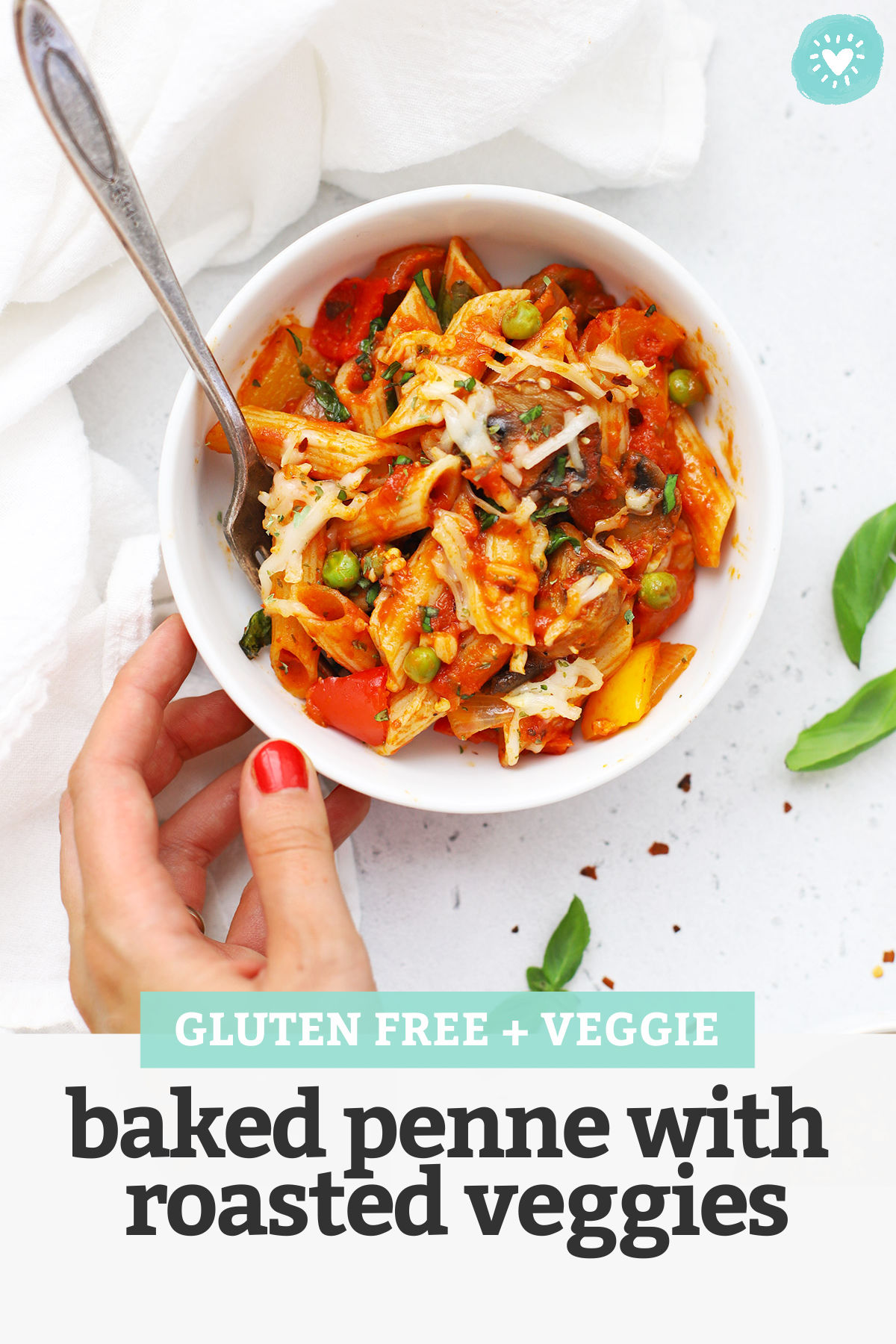 Setting down a bowl of gluten free baked penne with roasted veggies with text overlay that reads "Gluten-Free + Veggie Baked Penne with Roasted Veggies"