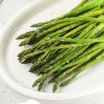 roasted asparagus spears on a white platter