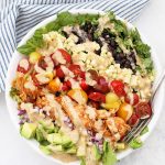 BBQ Ranch Chicken Salad in a large white bowl with a blue and white striped kitchen towel in the background.
