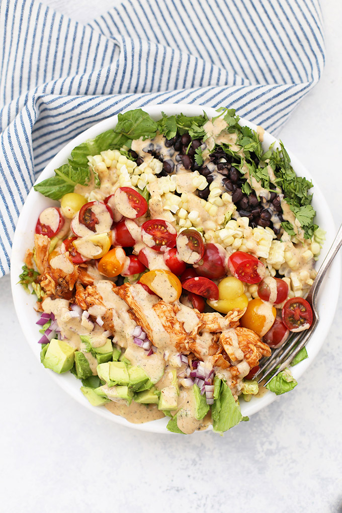 BBQ Ranch Chicken Salad in a large white bowl with a blue and white striped kitchen towel in the background. 