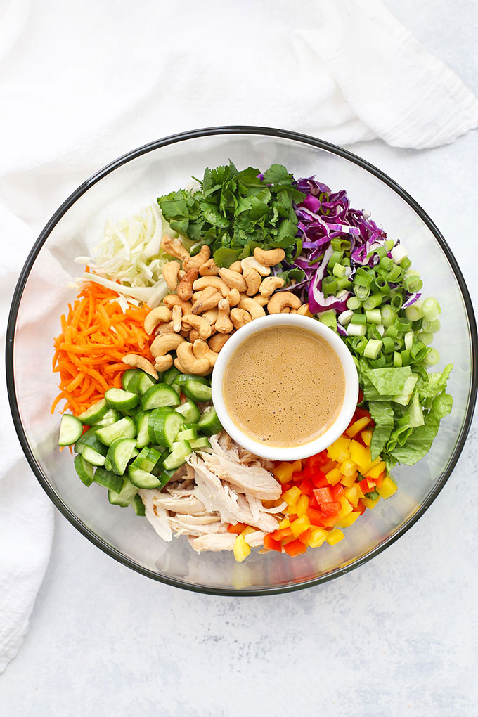 Thai Chopped Salad from One Lovely Life, with lettuce, cabbage, carrots, pepper, cucumber, green onions, cilantro, chicken, and Thai peanut sauce drizzle