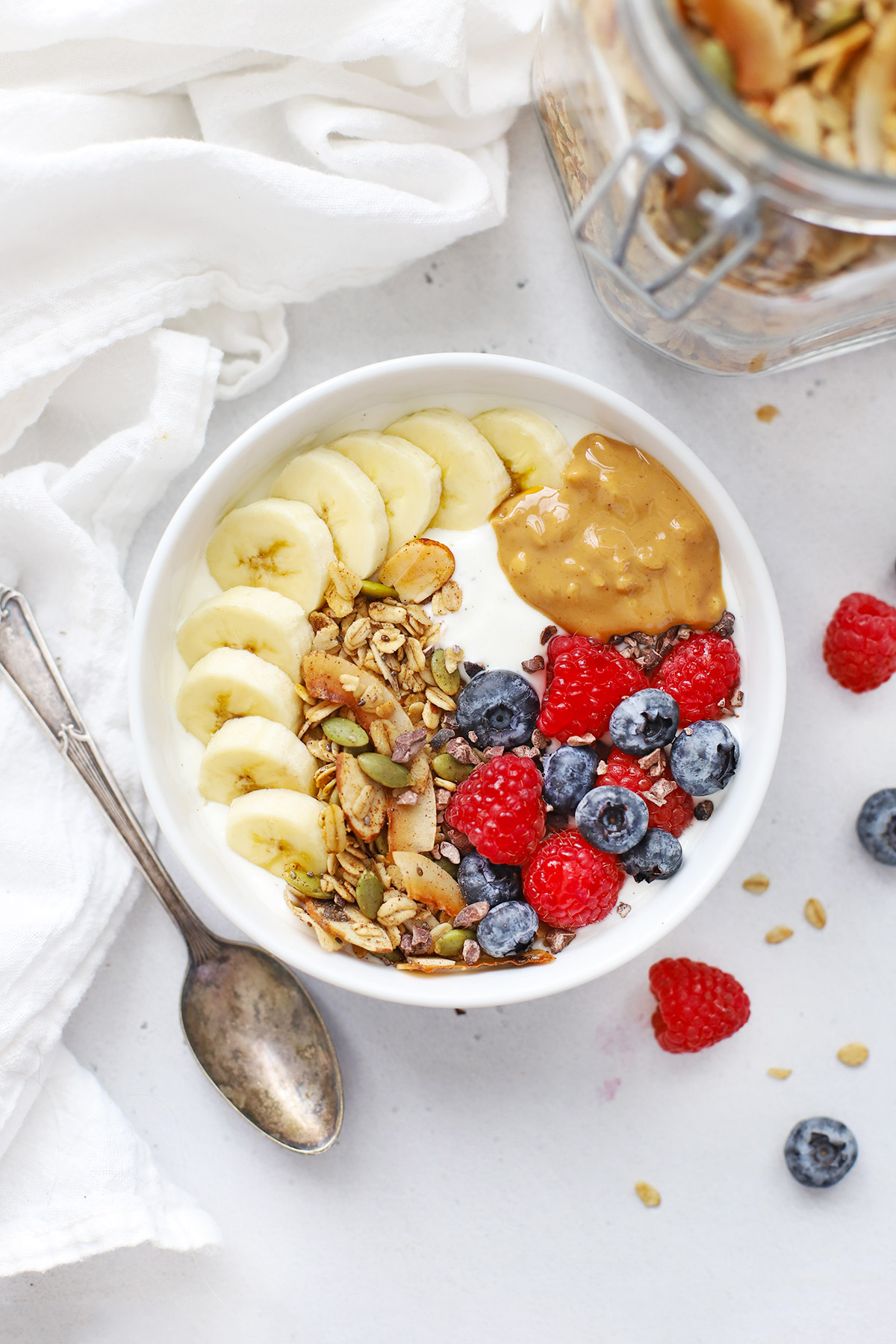 Overhead view of Yogurt Bowl with Warm Spiced Granola, fresh berries, sliced banana, and peanut butter
