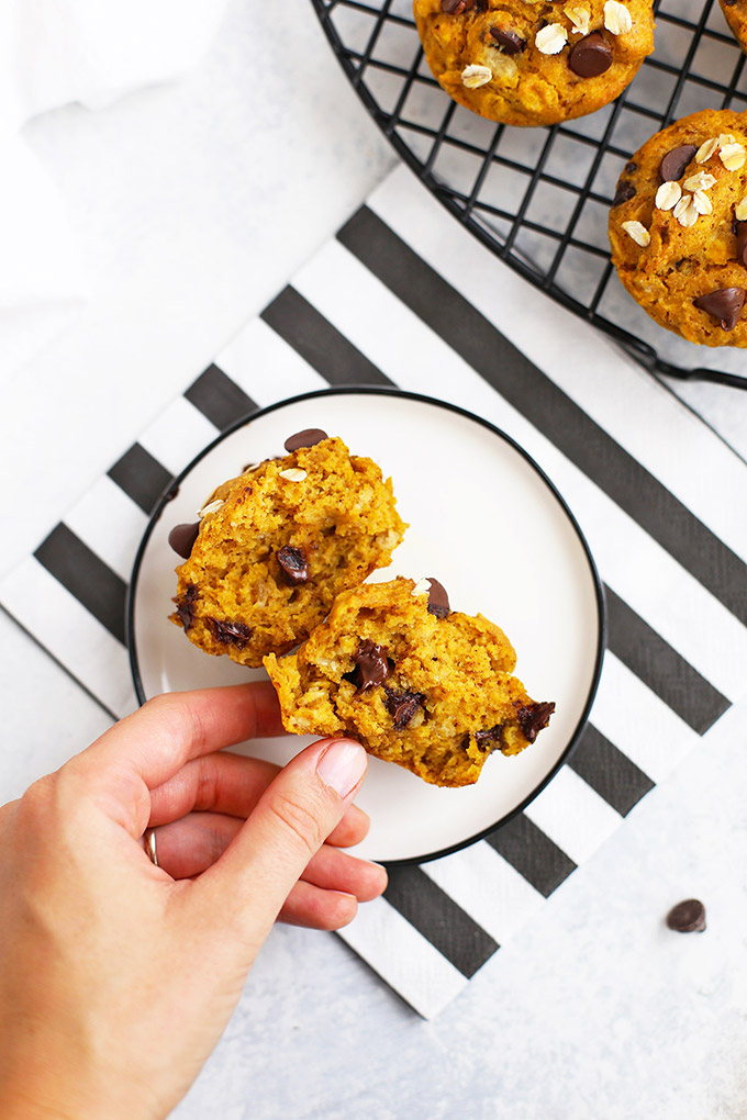 Hand reaching for Gluten Free Pumpkin Chocolate Chip Muffin on a plate
