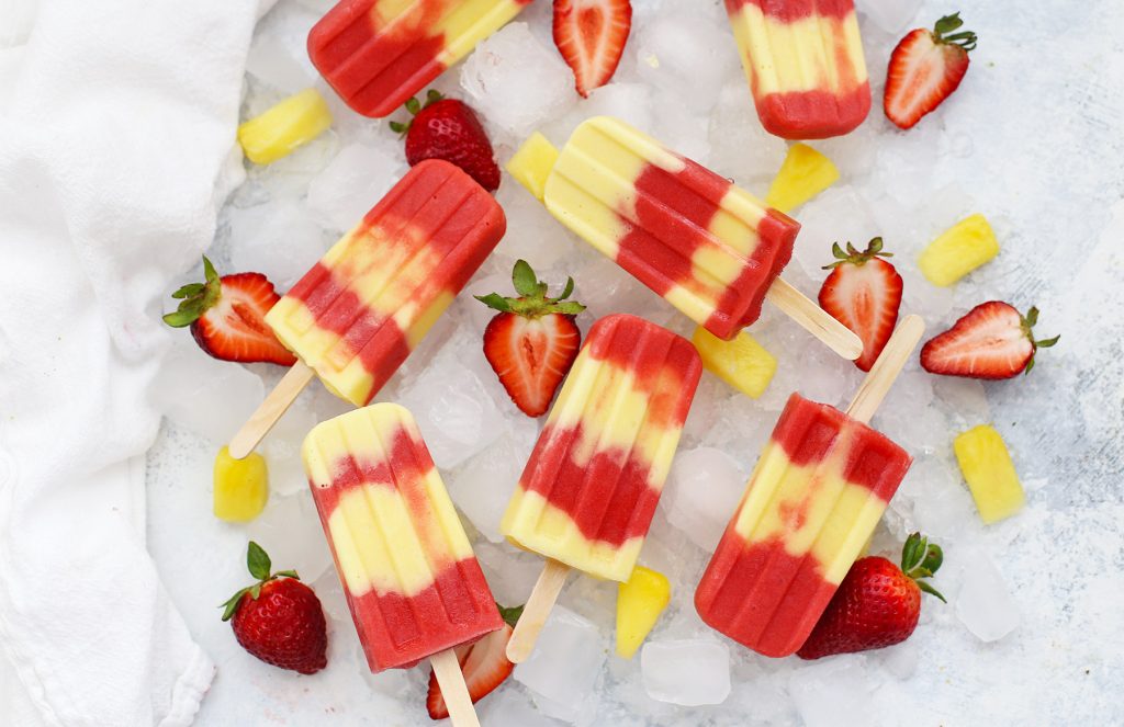 Overhead view of strawberry pineapple lava flow popsicles on a platter of ice