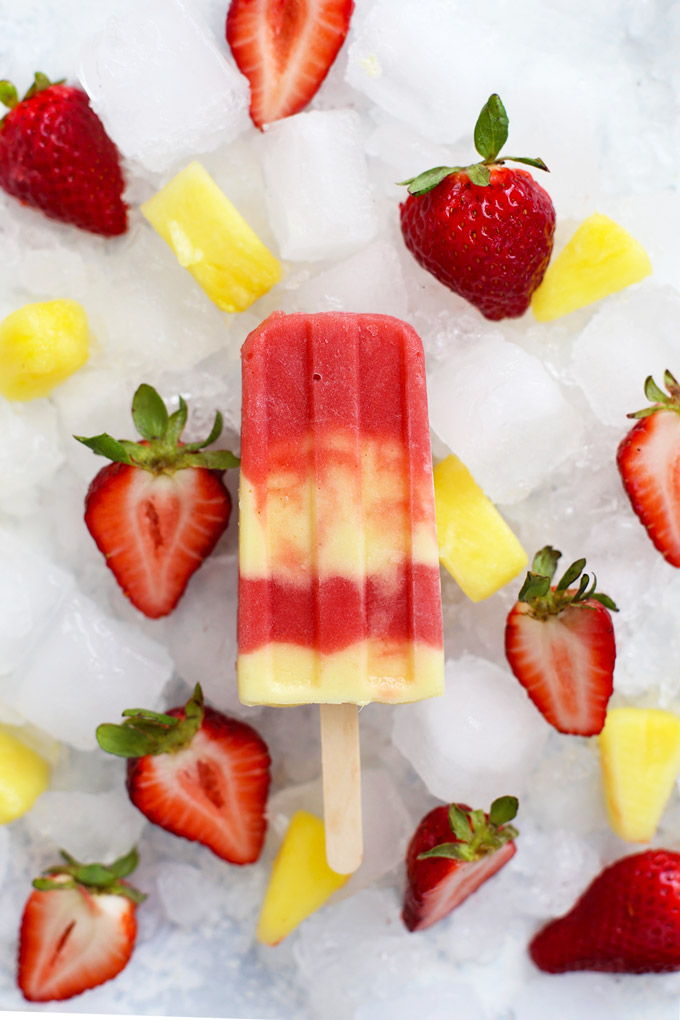 Lava Flow Popsicles - Creamy coconut pineapple swirled with fresh strawberry. Paleo, Vegan, and naturally sweetened!