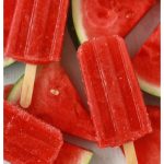 strawberry watermelon popsicles with wedges of fresh watermelon on a white background