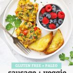 Overhead view of two slices of sausage and veggie breakfast bake, gluten free toast + fresh berries with text overlay that reads "Gluten-Free + Paleo Sausage + Veggie Breakfast Bake - perfect for holidays + meal prep + more!"