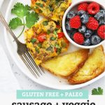slices of sausage and veggie breakfast bake on a plate with fresh berries + toast with text overlay that reads "Gluten-Free + Paleo Sausage + Veggie Breakfast Bake - perfect for holidays + meal prep + more!"