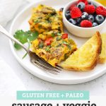 Front view of slices of sausage and veggie breakfast bake on a plate with fresh berries + toast with text overlay that reads "Gluten-Free + Paleo Sausage + Veggie Breakfast Bake - perfect for holidays + meal prep + more!"
