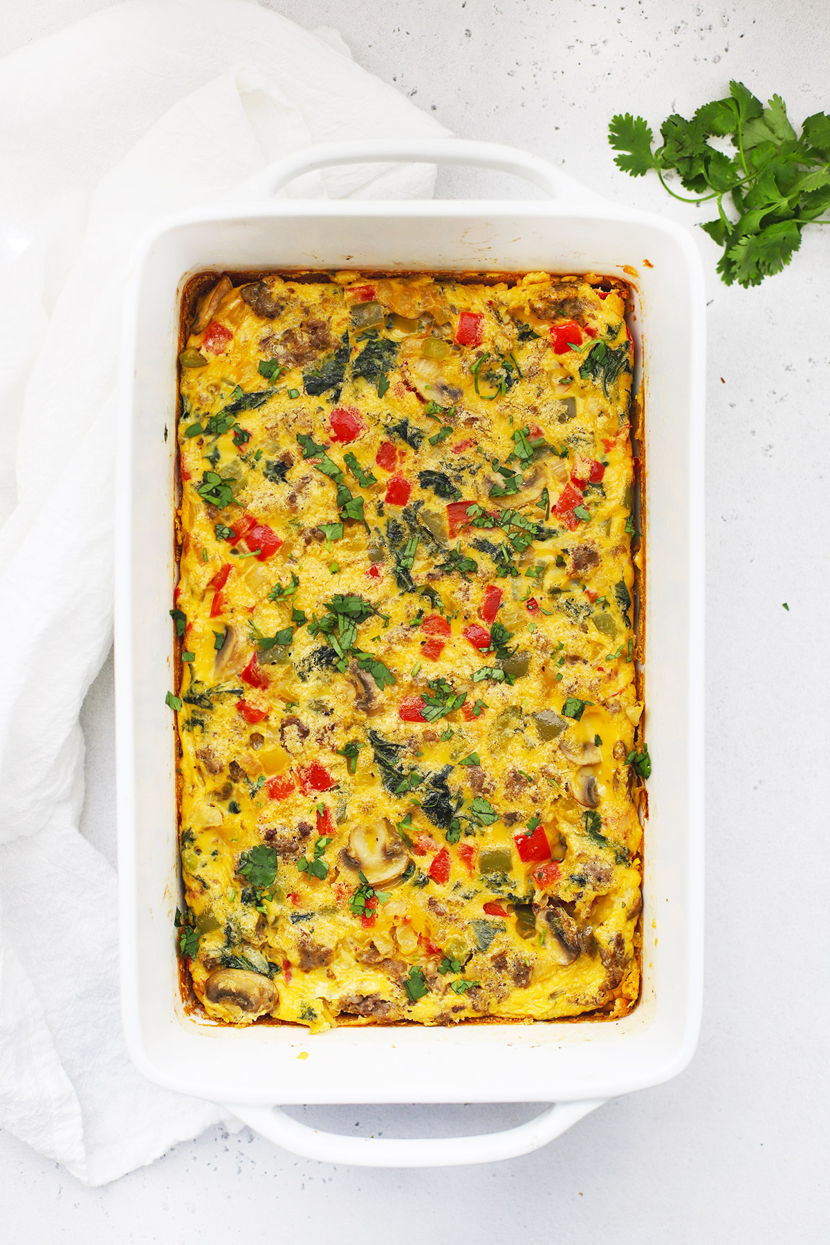Overhead view of sausage and veggie breakfast casserole in a white baking dish