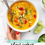 Setting down a bowl of Slow Cooker Thai Chicken + Butternut Squash Soup with text overlay that reads "GLuten-FREe + Easy! Slow Cooker Thai Chicken + Butternut Soup"