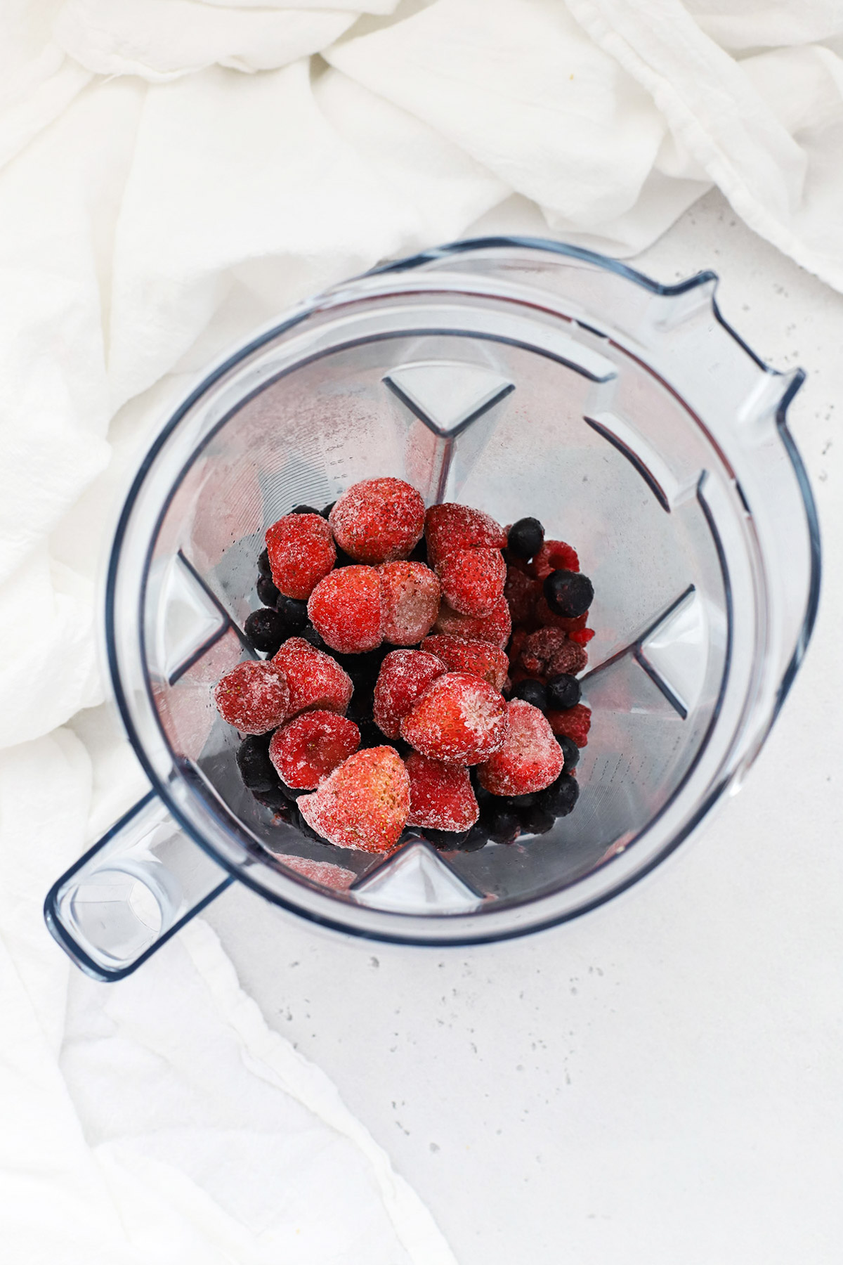 Adding frozen berries to a blender to make berry smoothies