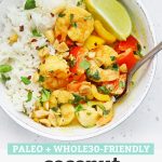 Overhead view of a bowl of paleo coconut shrimp curry with colorful veggies, crushed peanuts, and a fresh lime wedge with text overlay that reads "Paleo + Whole30 Friendly Coconut Shrimp Curry"