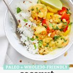 Close up overhead view of a bowl of coconut shrimp curry with chili flakes, crushed nuts, and a fresh lime wedge with text overlay that reads "Paleo + Whole30 Friendly Coconut Shrimp Curry"