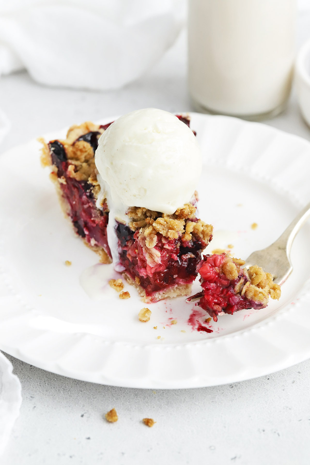 A slice of triple berry crumble pie topped with vanilla ice cream