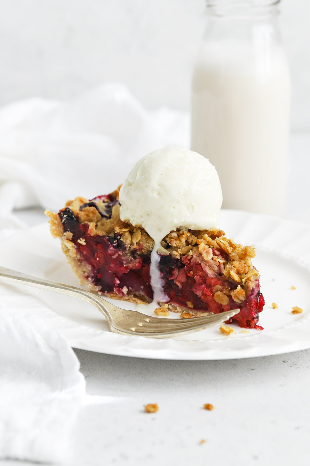 A slice of triple berry crumble pie topped with vanilla ice cream