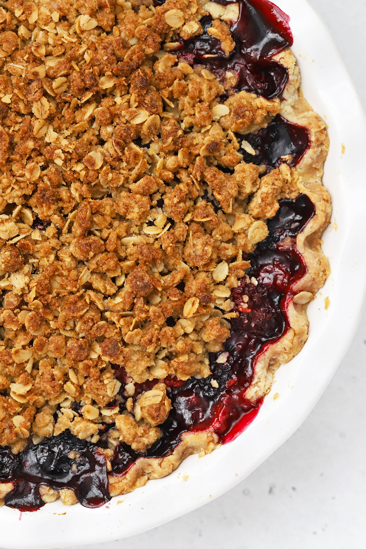 Close up view of a freshly baked triple berry crumble pie with bubble berry filling and golden crumble topping