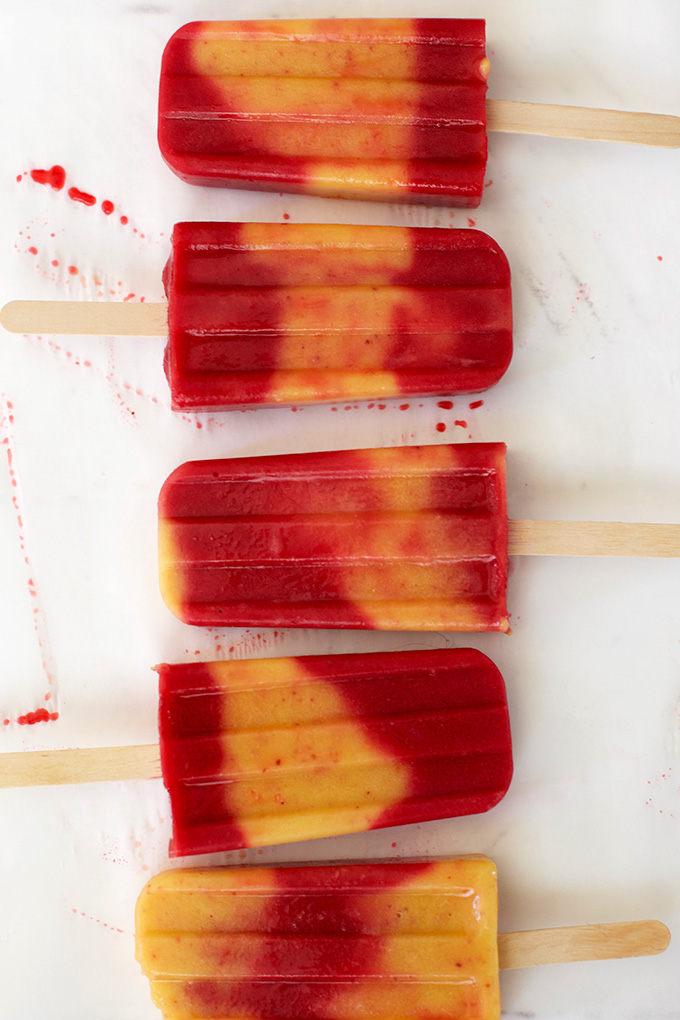 Creamy peach and bright, tangy raspberry swirl popsicles. These are so good!