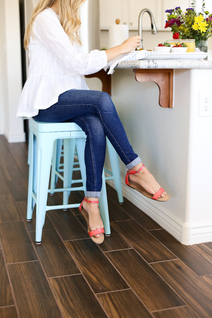 Classic look with a pop of color. Wood-look tile, aqua metal stools, and white walls make for a clean, bright kitchen! 