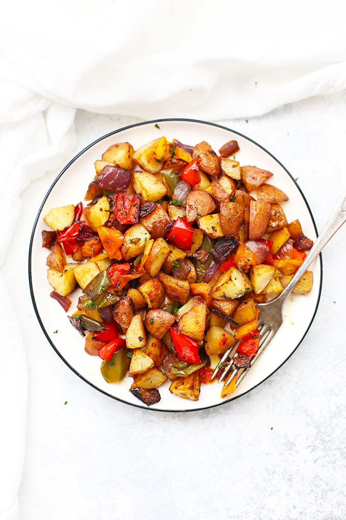 Plate of roasted breakfast potatoes and veggies with a fork ready to take a bite.