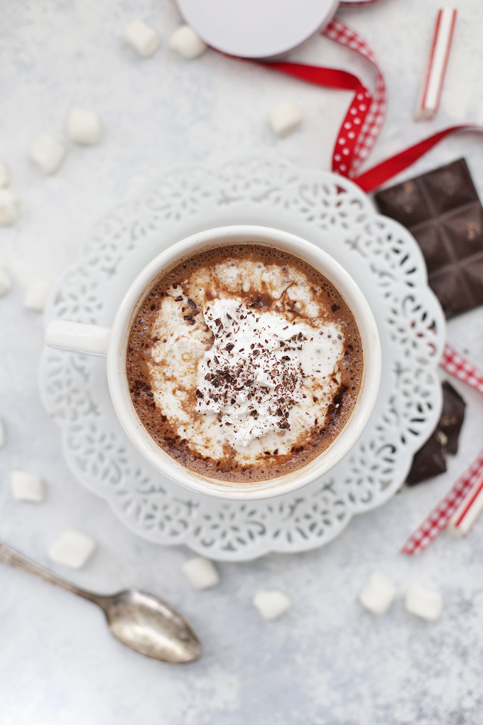 Overhead view of vegan hot chocolate topped with coconut whipped cream and shaved chocolate. 