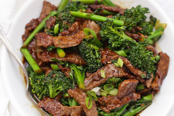 a bowl of beef and broccoli on a white background