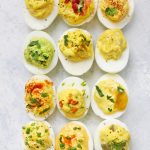 Close up image of 12 flavors of paleo deviled eggs on a white background