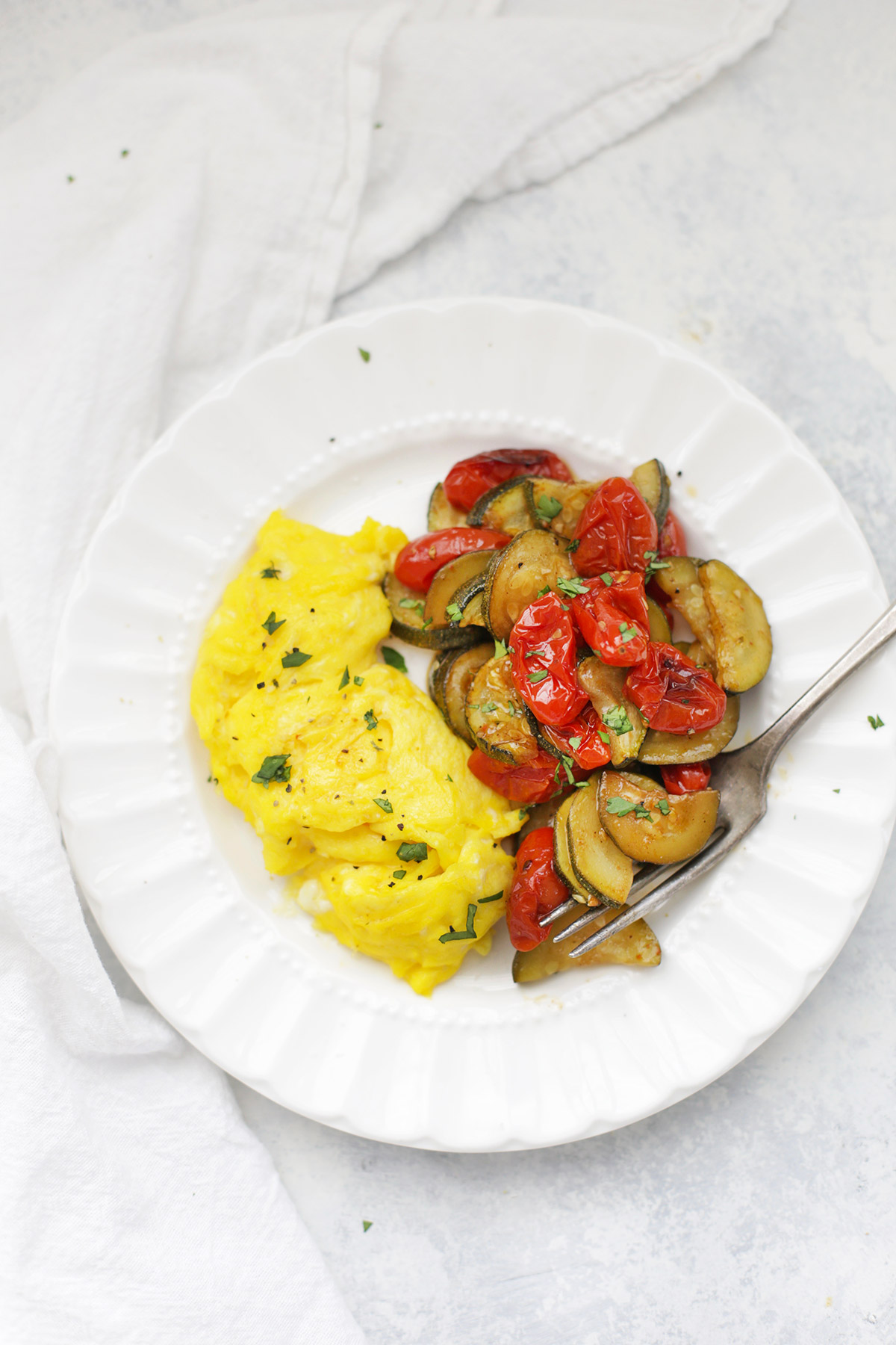 Soft-scrambled eggs with simply roasted zucchini and tomatoes on the side.