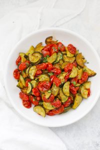A bowl of simply roasted zucchini and tomatoes with fresh herbs.