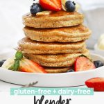 Close up Front view of a stack of blender banana oatmeal pancakes topped with sliced bananas, fresh berries, and syrup with text overlay that reads "gluten-free + dairy-free blender banana oatmeal pancakes"