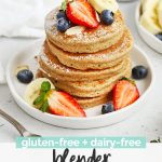 Close up Front view of a stack of blender banana oatmeal pancakes topped with sliced bananas, fresh berries, and powdered sugar with text overlay that reads "gluten-free + dairy-free blender banana oatmeal pancakes"