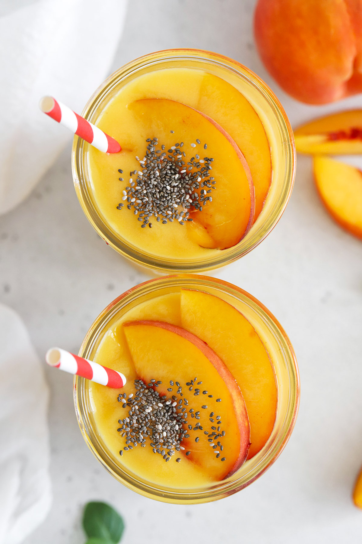 overhead view of peach mango smoothies topped with fresh peach slices and chia seeds