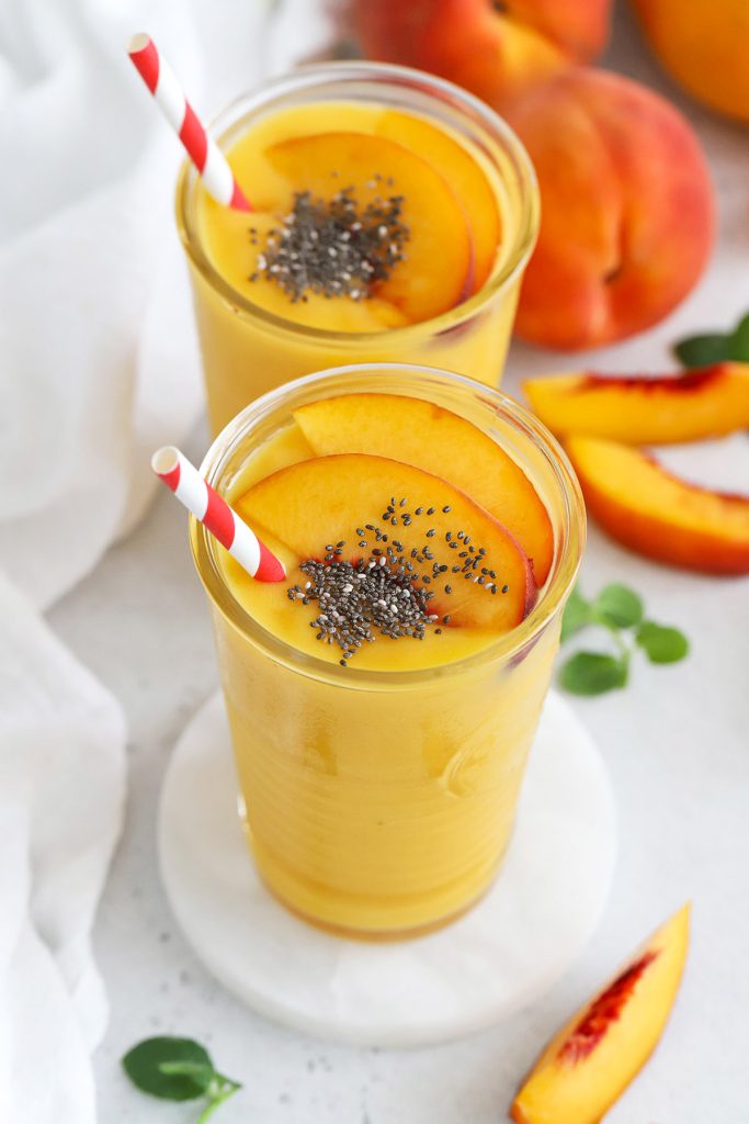 front view of peach mango smoothies topped with fresh peach slices and chia seeds
