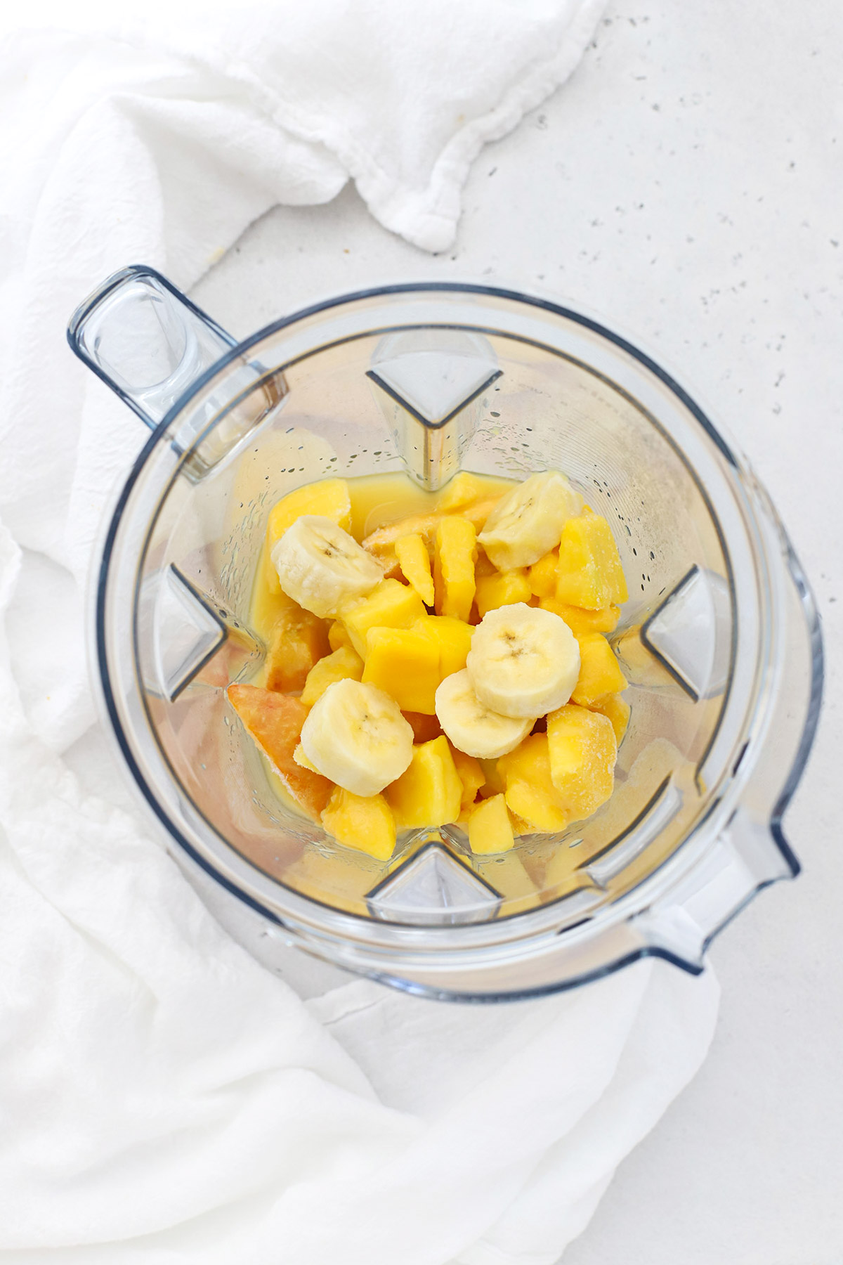 peach mango smoothie ingredients in a blender ready to puree