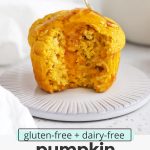 Front view of a gluten-free pumpkin muffin with a bite out of it, being drizzled with honey with text overlay that reads "gluten-free + dairy-free pumpkin cornbread muffins: light + fluffy + delightful"