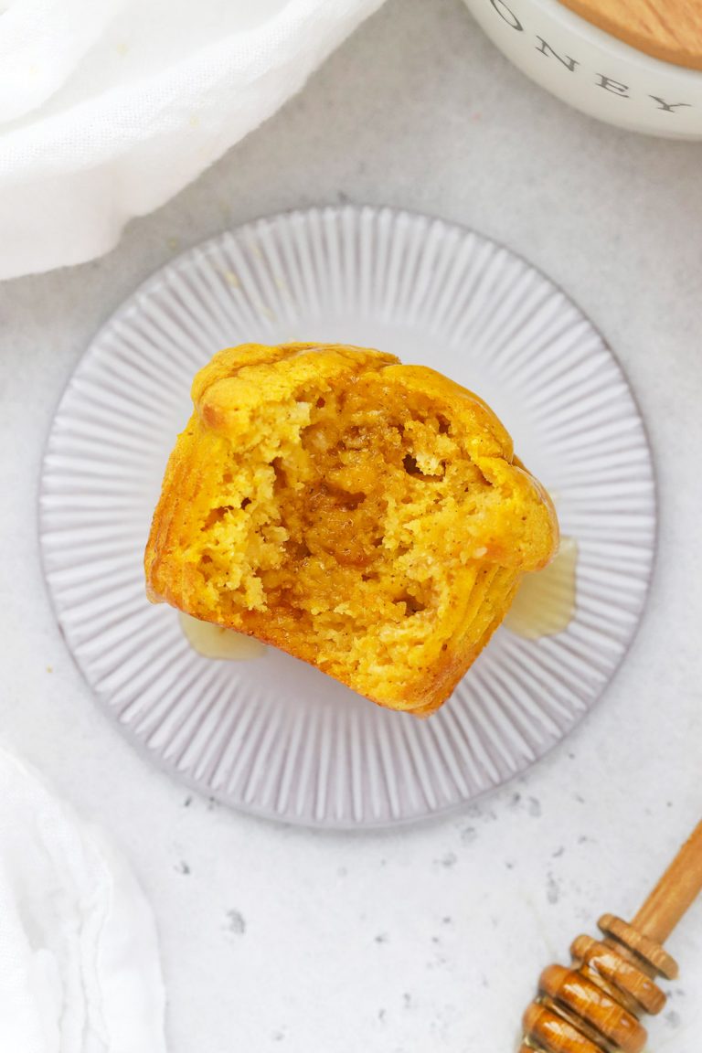 Overhead view of a gluten-free pumpkin muffin with a bite out of it, drizzled with honey