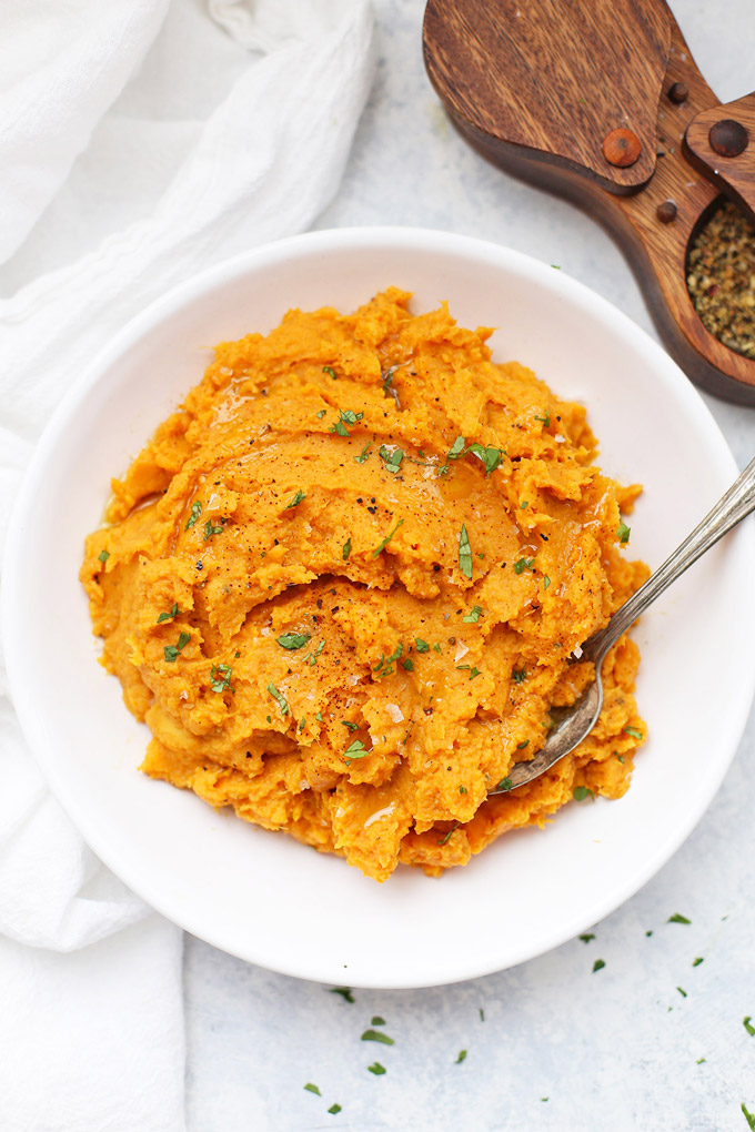 Overhead view of a bowl of chipotle mashed sweet potatoes topped with fresh herbs. 