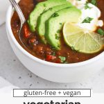 Front view of two bowls of vegan black bean soup topped with plain yogurt, sliced avocado, cilantro, and lime with text overlay that reads "gluten-free + vegan vegetarian black bean soup: warm + cozy + healthy"