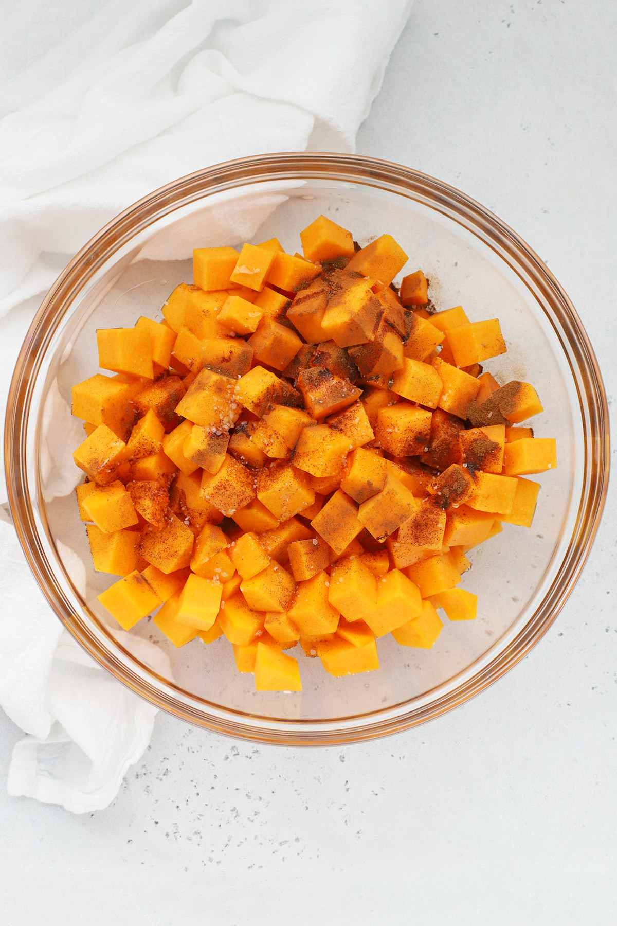 Overhead view of ingredients for roasted cinnamon butternut squash in a mixing bowl