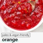 Overhead view of orange honey cranberry sauce with text overlay that reads "paleo & vegan-friendly orange honey cranberry sauce naturally sweetened + so good!"