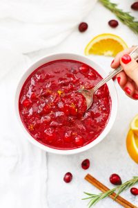 Overhead view of a spoon dipped into a white bowl of naturally sweetened orange honey cranberry sauce