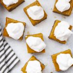 Overhead view of squares of gluten-free pumpkin pie bars with ginger cookie crust on a white background