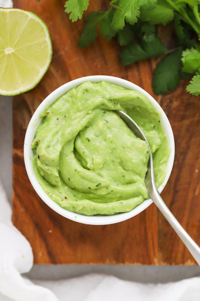 Spoon dipping into a bowl of citrus avocado sauce