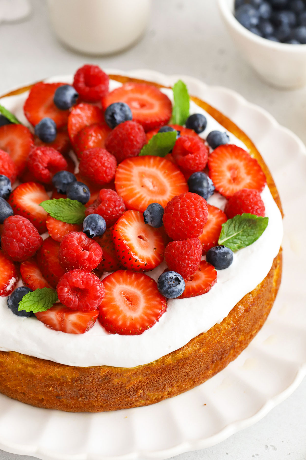 almond flour lemon cake topped with coconut whipped cream and fresh berries