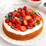 almond flour lemon cake topped with coconut whipped cream and fresh berries