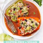 Mexican Stuffed Peppers with Quinoa and Black Beans on a White Plate with Red Enchilada Sauce with text overlay that reads "Gluten-Free + Vegan Tex-Mex Quinoa Stuffed Peppers"