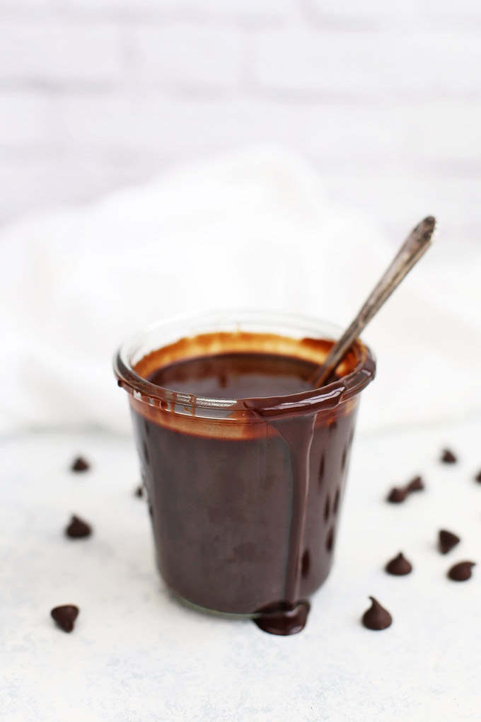Vegan Hot Fudge Sauce in a jar with a little fudge sauce dripping down the side. 