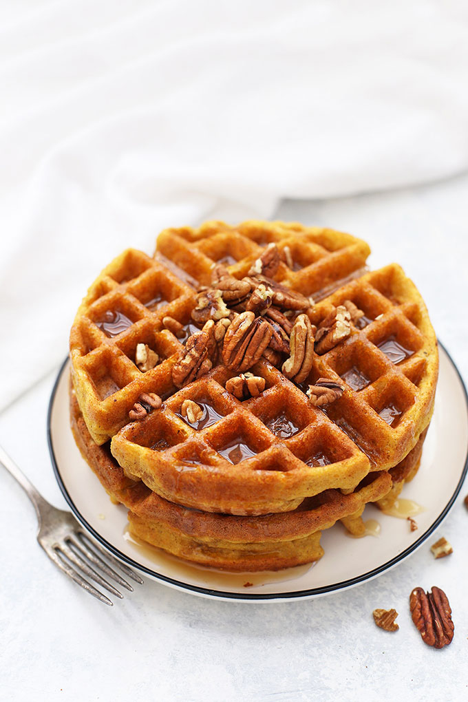 Stack of Almond Flour Pumpkin Waffles with pecans and maple syrup. 