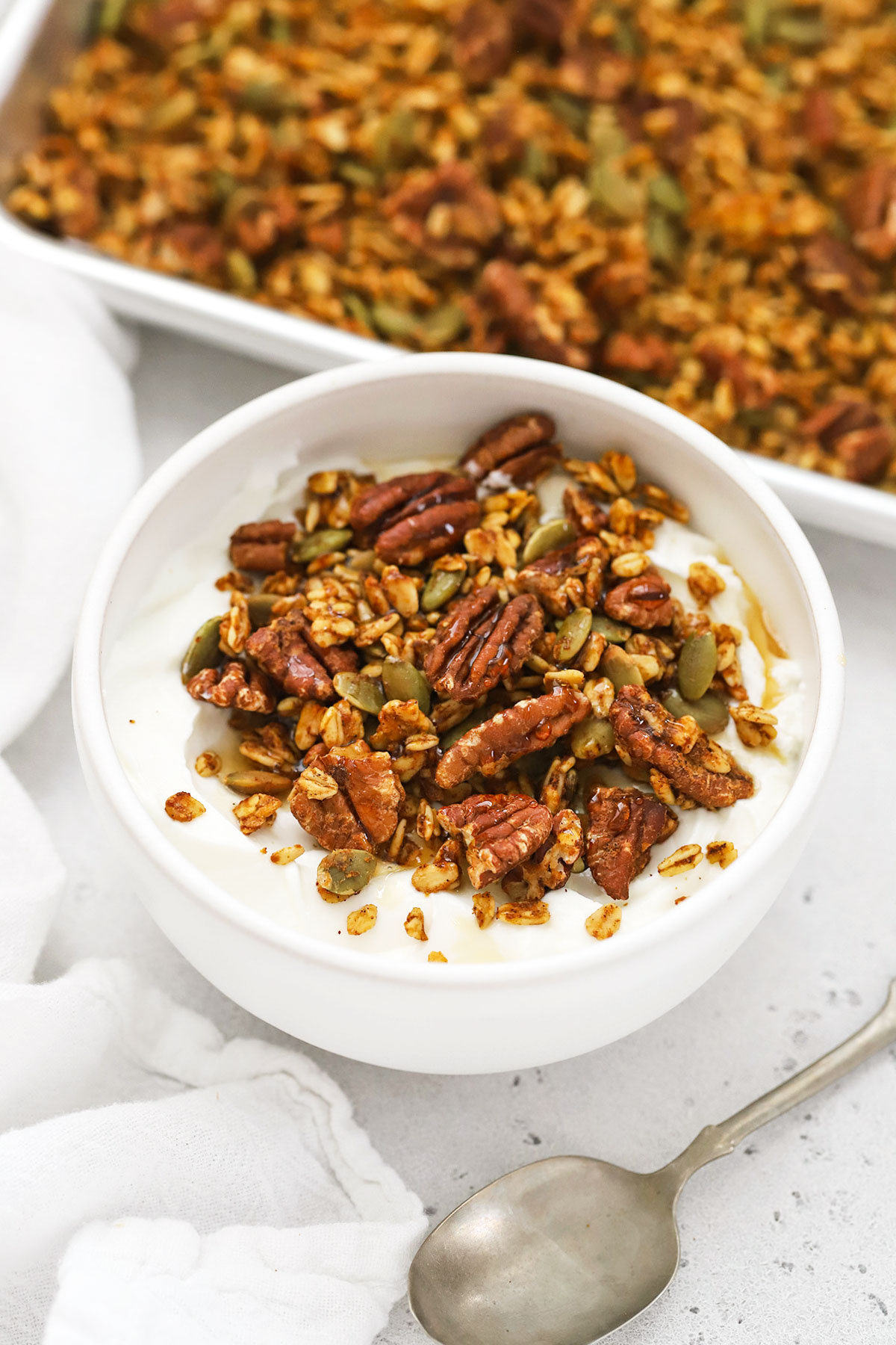 plain greek yogurt topped with pumpkin granola and a drizzle of maple syrup