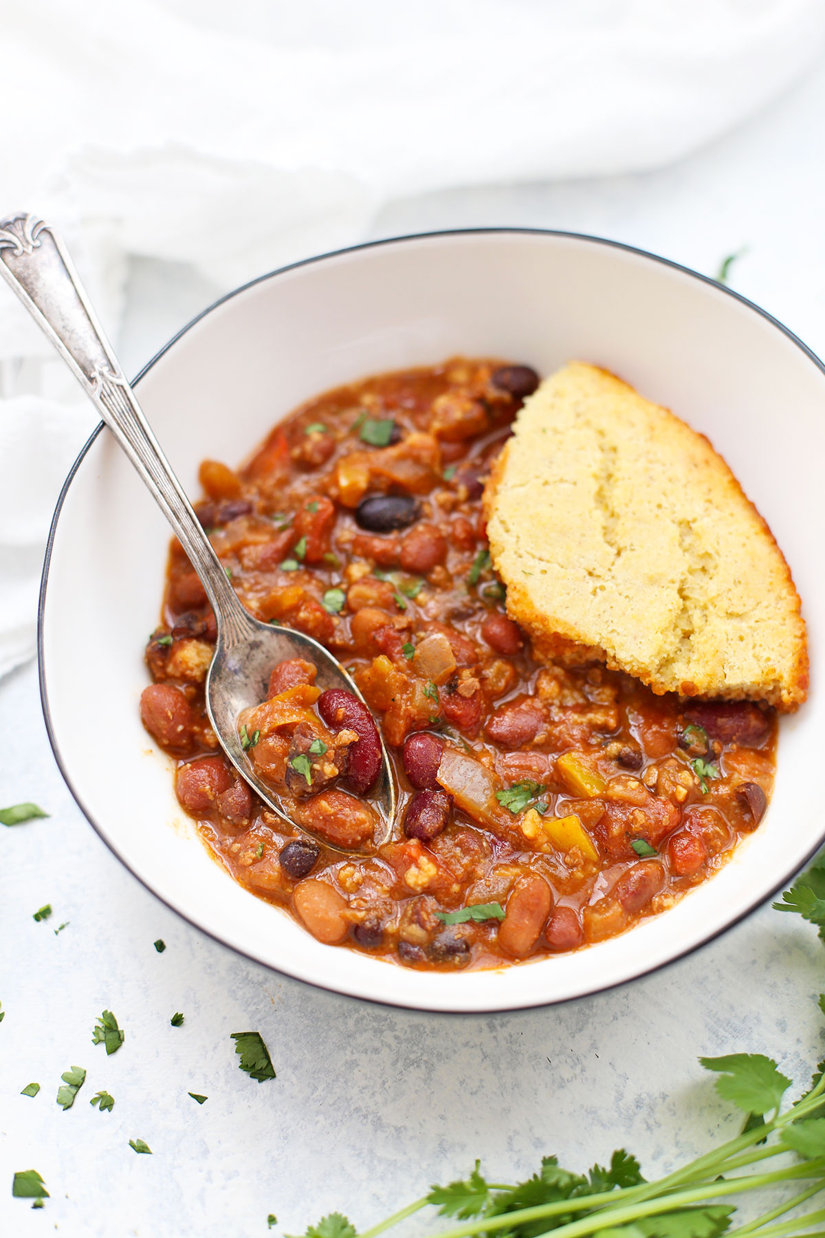 Front view of chili and cornbread in a bowl, with a spoon